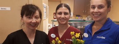 Three peopleCare staff members holding daffodils