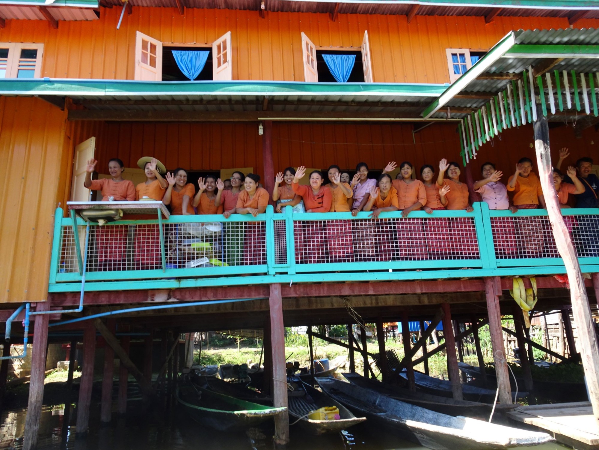 Group of Myanmar residents waving from a balcony