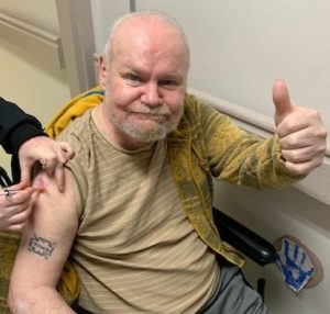 Long-term care resident smiles and gives a thumbs up as he receives his COVID-19 vaccine