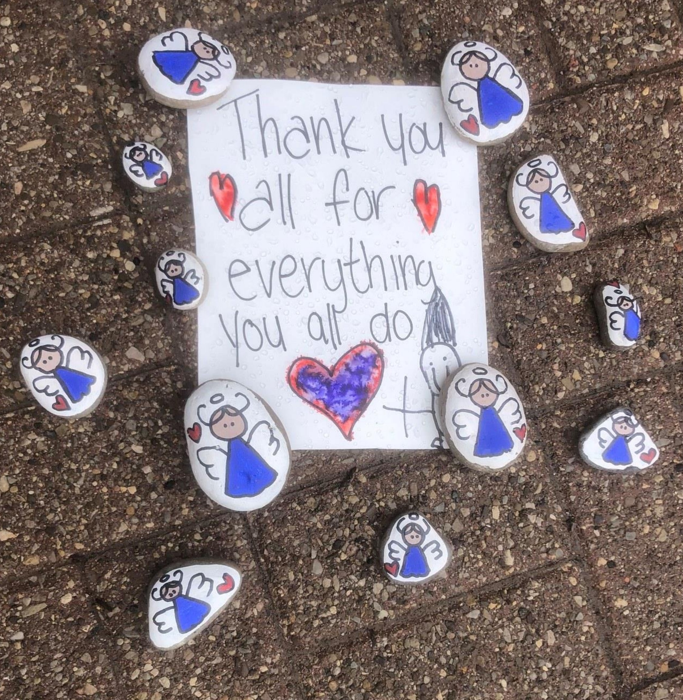 A hand written thank you note and painted rocks placed on the ground outside a long term care home