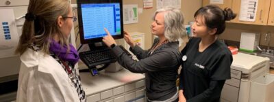 Three team members standing around and looking at a computer together