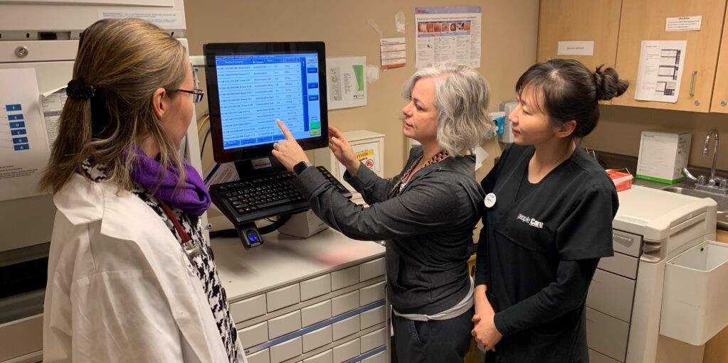 Three team members standing around and looking at a computer together