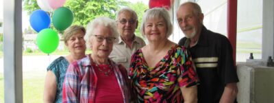 peopleCare resident standing with her designated family caregiver and other family members at a birthday party